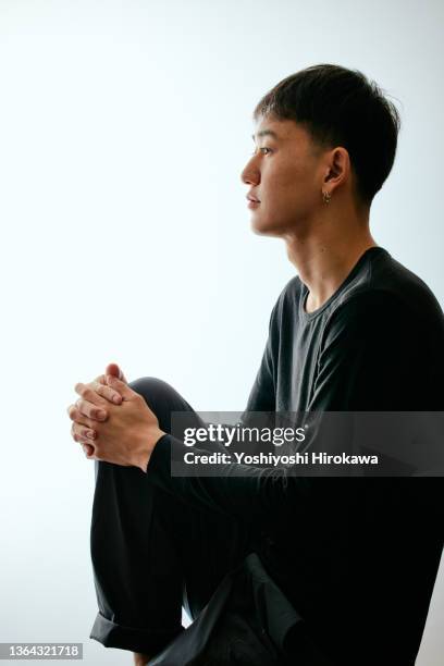 profile of surfer holding his knees - young man asian silhouette stock pictures, royalty-free photos & images