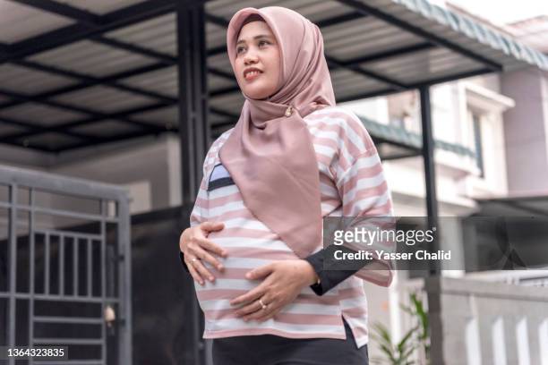 pregnant woman walking in neighbourhood - pregnant muslim stockfoto's en -beelden