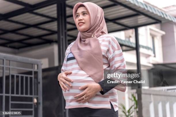 pregnant woman walking in neighbourhood - pregnant muslim stock pictures, royalty-free photos & images