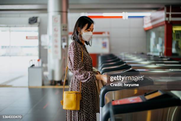 young asian woman passing through gate at subway station - entering turnstile stock pictures, royalty-free photos & images