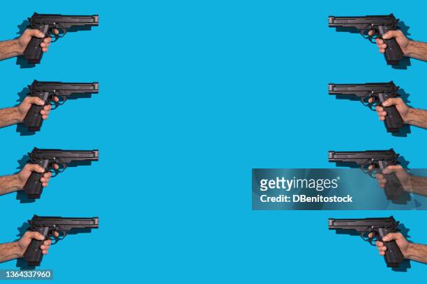 eight opposing hands holding a gun and pointing at each other, with hard shadow, on a blue background, murder, violence, gun, shooting, police, bodyguard, hitman and army concept. - hand holding gun stockfoto's en -beelden