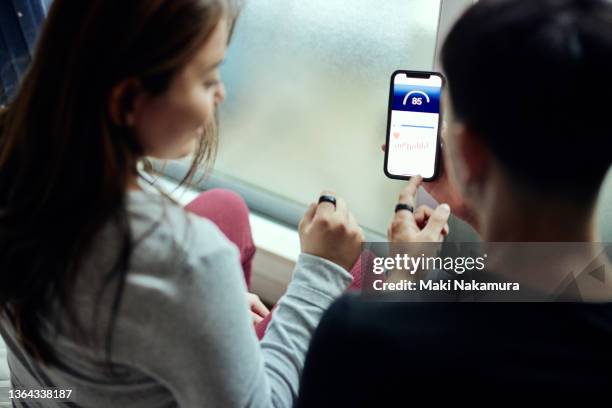 gen z male and female couples talking while looking at the gadget app for health. - intelligenz stock-fotos und bilder