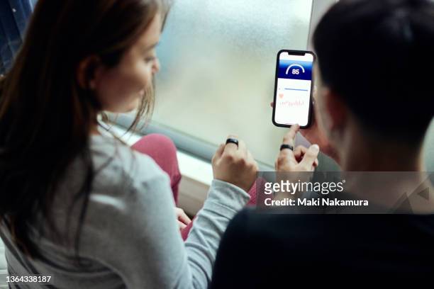 gen z male and female couples talking while looking at the gadget app for health. - screening of at t audience networks mr mercedes arrivals stockfoto's en -beelden