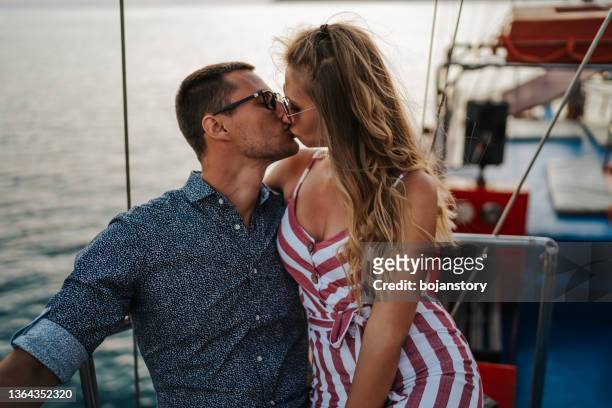 romantisches paar, das sich bei sonnenuntergang auf der yacht küsst - kiss booth stock-fotos und bilder