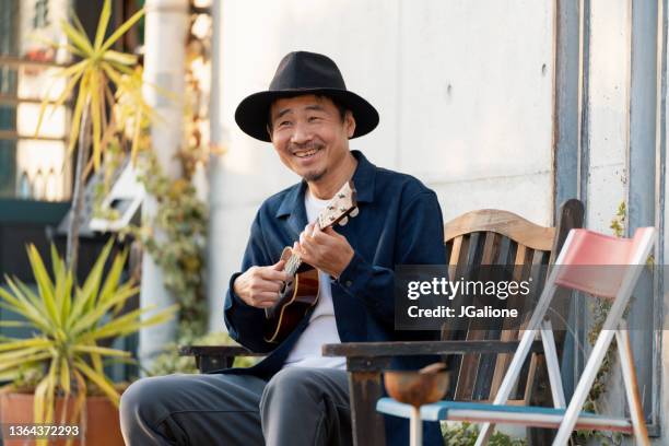 ritratto di un uomo maturo dall'aspetto felice con un ukulele - plucking an instrument foto e immagini stock