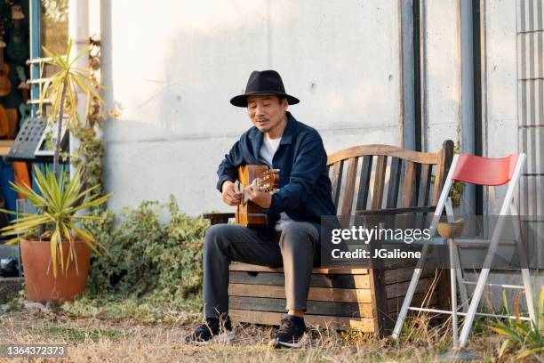hombre japonés maduro tocando la guitarra al aire libre - melody maker fotografías e imágenes de stock