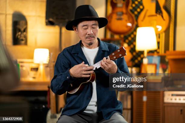 mature japanese male playing the ukulele - professional musician stock pictures, royalty-free photos & images