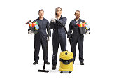 Team of professional cleaners in uniforms with a vacuum cleaner and cleaning supplies