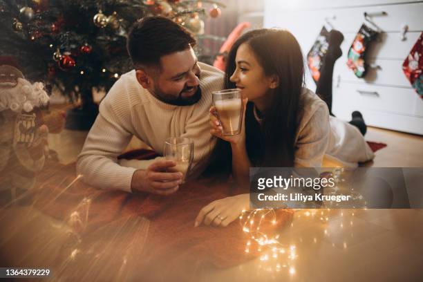 happy couple drinking coffee under the christmas tree. - christmas coffee imagens e fotografias de stock
