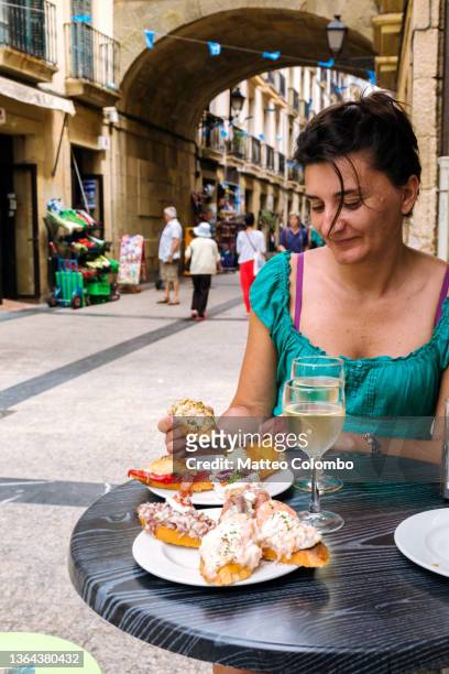 woman eating pintxos (tapas) of san sebastian, spain - san sebastián spanien stock-fotos und bilder