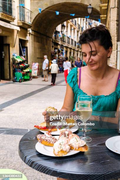 woman eating pintxos (tapas) of san sebastian, spain - spain san sebastian imagens e fotografias de stock