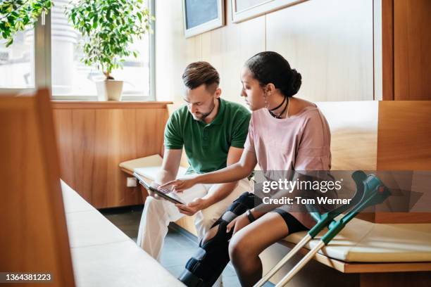 injured woman talking to hospital nurse following ct scan - crutch stock-fotos und bilder