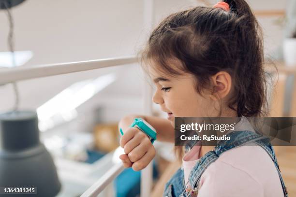 cute girl using a smartwatch at home - smart watch on wrist stock pictures, royalty-free photos & images