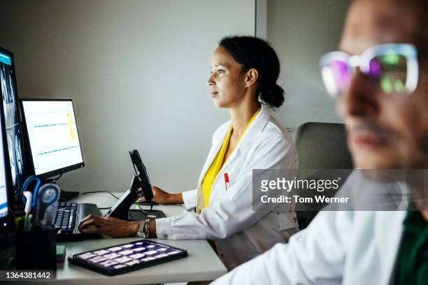 doctors focusing on computer monitors during ct scan - spital raum hell stock-fotos und bilder