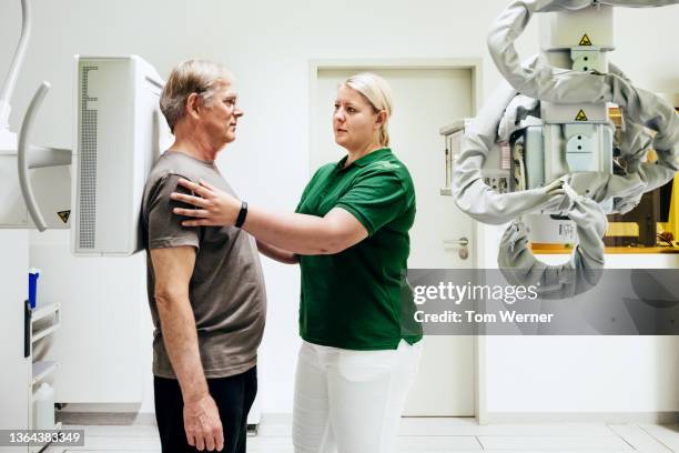 technician aligning patient before taking x-ray of his chest - röntgen stock-fotos und bilder