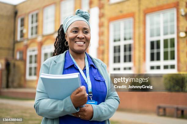 cheerful black teacher standing outside education building - professor imagens e fotografias de stock