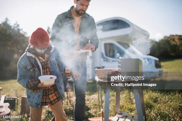 mid adult man with his son camping and having barbecue in autumn day. - car grill stock pictures, royalty-free photos & images