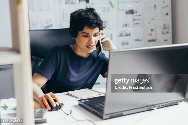 a beautiful latin-american multitasking: scrolling on her computer while using her mobile phone - using computer mouse stock pictures, royalty-free photos & images
