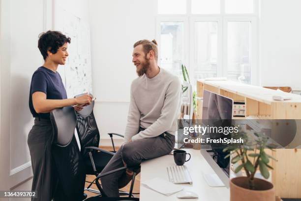 eine erfolgreiche geschäftsfrau, die mit ihrem männlichen kollegen über etwas spricht, das nichts mit der arbeit zu tun hat - happy male side view stock-fotos und bilder