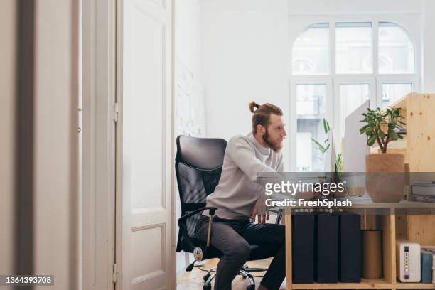 una foto laterale di un bell'uomo d'affari che lavora nel suo ufficio al suo computer - delusione foto e immagini stock