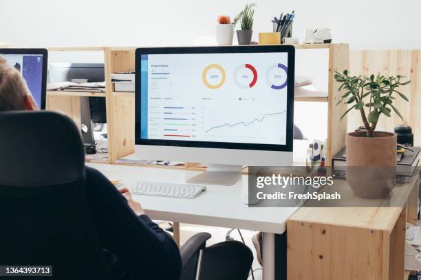 an unrecognizable male sitting in his office at his desk and watching some statistics on his computer - excited money computer stock pictures, royalty-free photos & images