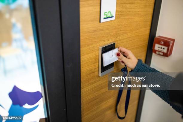 unrecognizable caucasian female staff using id enter key to open the door at the building - access stockfoto's en -beelden