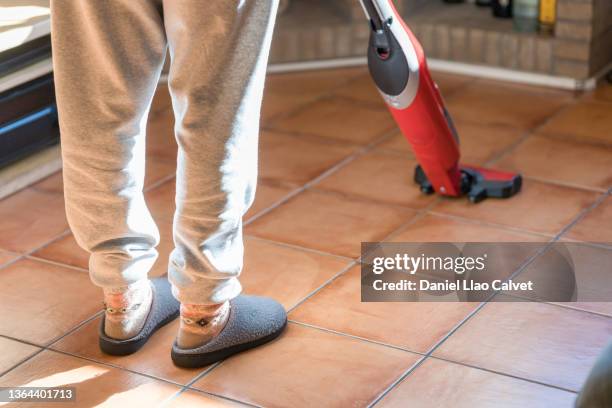 low section of woman using vacuum cleaner on living room - aspirador stockfoto's en -beelden