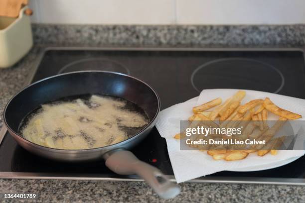 frying pan with oil in which potatoes are frying - aspirador stockfoto's en -beelden