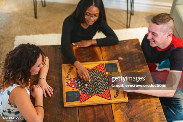 generation z multiracial group of friends cooking playing playing chinese checkers relaxing and communicating in modern home photo series - boardgame stockfoto's en -beelden