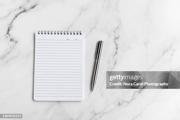 note pad and pen on marble desk - office work flat lay stock-fotos und bilder