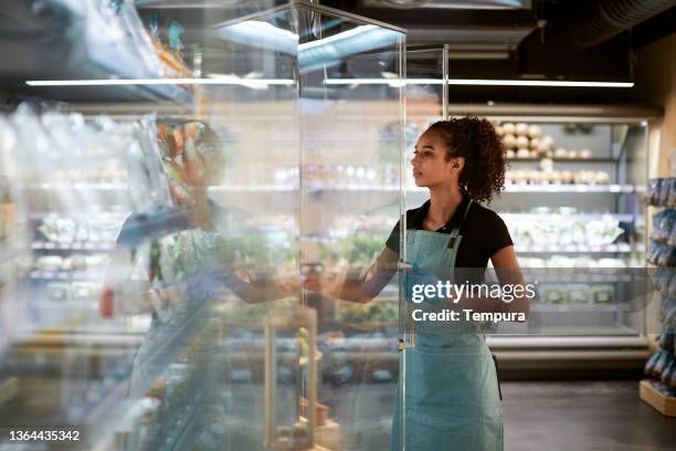 a grocery store employee adjusting products in the fridge. - refrigerated section supermarket stock pictures, royalty-free photos & images