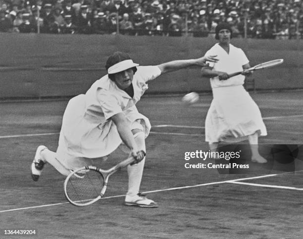 Helen Wills of the United States reaches to play a forehand return as compatriot partner Hazel Wightman looks on during their Women's Doubles Final...