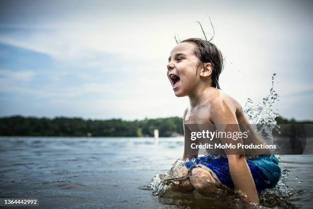 boy jumping into lake - leren korte broek stockfoto's en -beelden