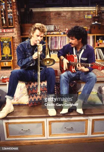 View of American Pop musicians Daryl Hall , on trombone, and John Oates, on guitar, both of the duo Hall and Oates, during an MTV interview at...