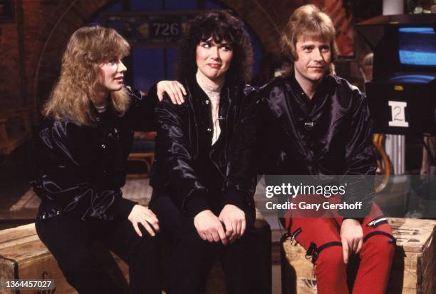 View, from left, American Rock musicians Nancy Wilson, Ann Wilson, and Howard Leese, all of the group Heart, as they sit on crates during an...