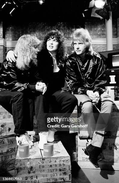 View, from left, American Rock musicians Nancy Wilson, Ann Wilson, and Howard Leese, all of the group Heart, as they sit on crates during an...