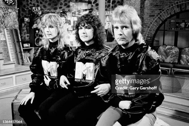 View, from left, American Rock musicians Nancy Wilson, Ann Wilson, and Howard Leese, all of the group Heart, as they sit on crates during an...