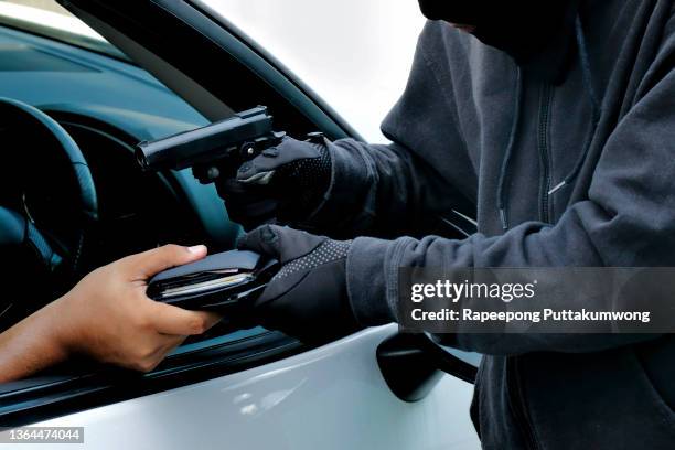 masked burglar pointing a gun at the driver - gangster stock pictures, royalty-free photos & images