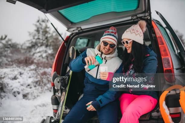 the couple sits in the trunk of the car and drinks tea - wintersport stockfoto's en -beelden