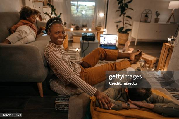 smiling woman watching movie on projector with family - home cinema stock pictures, royalty-free photos & images