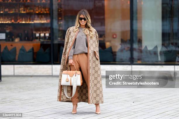 Influencer Gitta Banko wearing a light brown and camel colored crystal embellished GG monogram jumbo cape coat by Gucci, light brown sweatpants by...