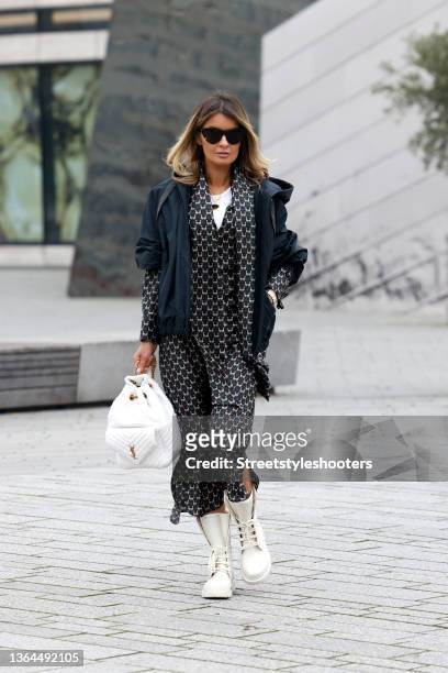 Influencer Gitta Banko wearing a black long dress with animal print by Max Mara, a black jacket by Brunello Cucinelli, white boots by Dior,...