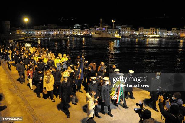 People taking part in a candlelight vigil to mark the exact time that the Costa Concordia ship crashed 10 years ago carry a Crown of Flowers in...