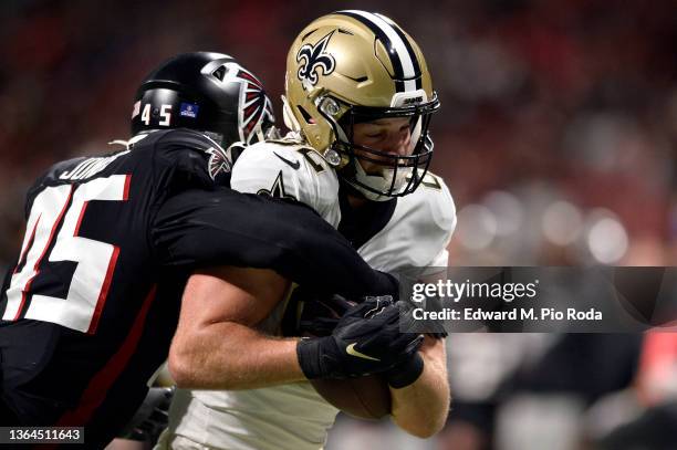 Adam Trautman of the New Orleans Saints runs while being tackled by Deion Jones of the Atlanta Falcons in the first half at Mercedes-Benz Stadium on...
