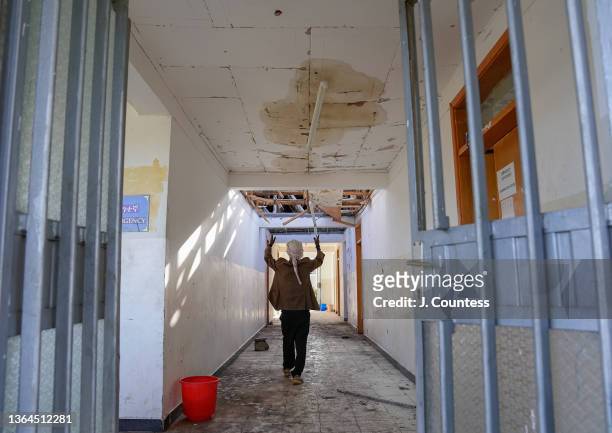 Guard points to the damage to the roof and ceiling of the Haik Health Center caused by artillery fire during the 2021 TPLF invasion and occupation of...