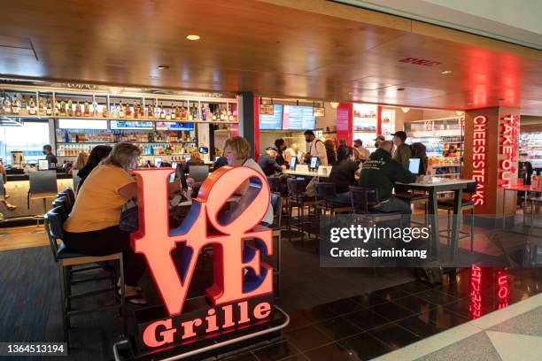 travelers dining at love grill inside the terminal of philadelphia international airport - philadelphia airport stock pictures, royalty-free photos & images