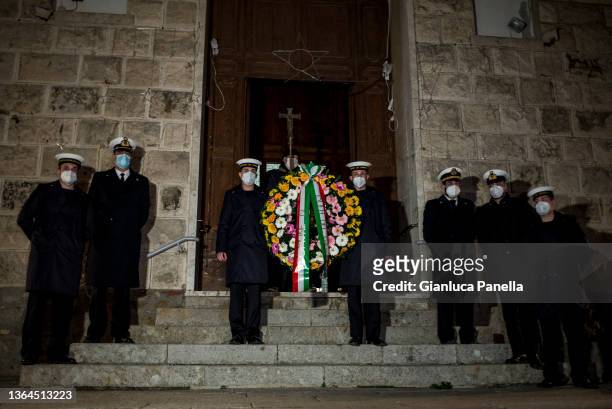 Members of the Coast Guard hold the wreath in front of the Church of San Lorenzo before the torchlight procession in memory of the victims on the...