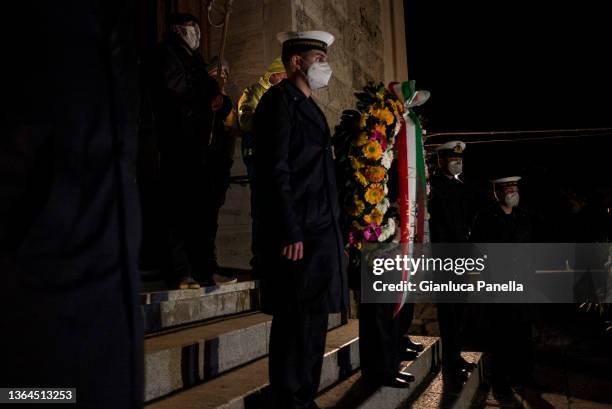 Members of the Coast Guard hold the wreath in front of the Church of San Lorenzo before the torchlight procession in memory of the victims on the...