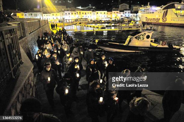 People taking part in a candlelight vigil to mark the exact time that the Costa Concordia cruise ship sank 10 years ago carry a Crown of Flowers in...