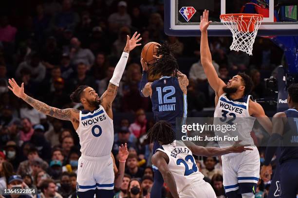 Ja Morant of the Memphis Grizzlies goes to the basket between D'Angelo Russell of the Minnesota Timberwolves and Karl-Anthony Towns of the Minnesota...